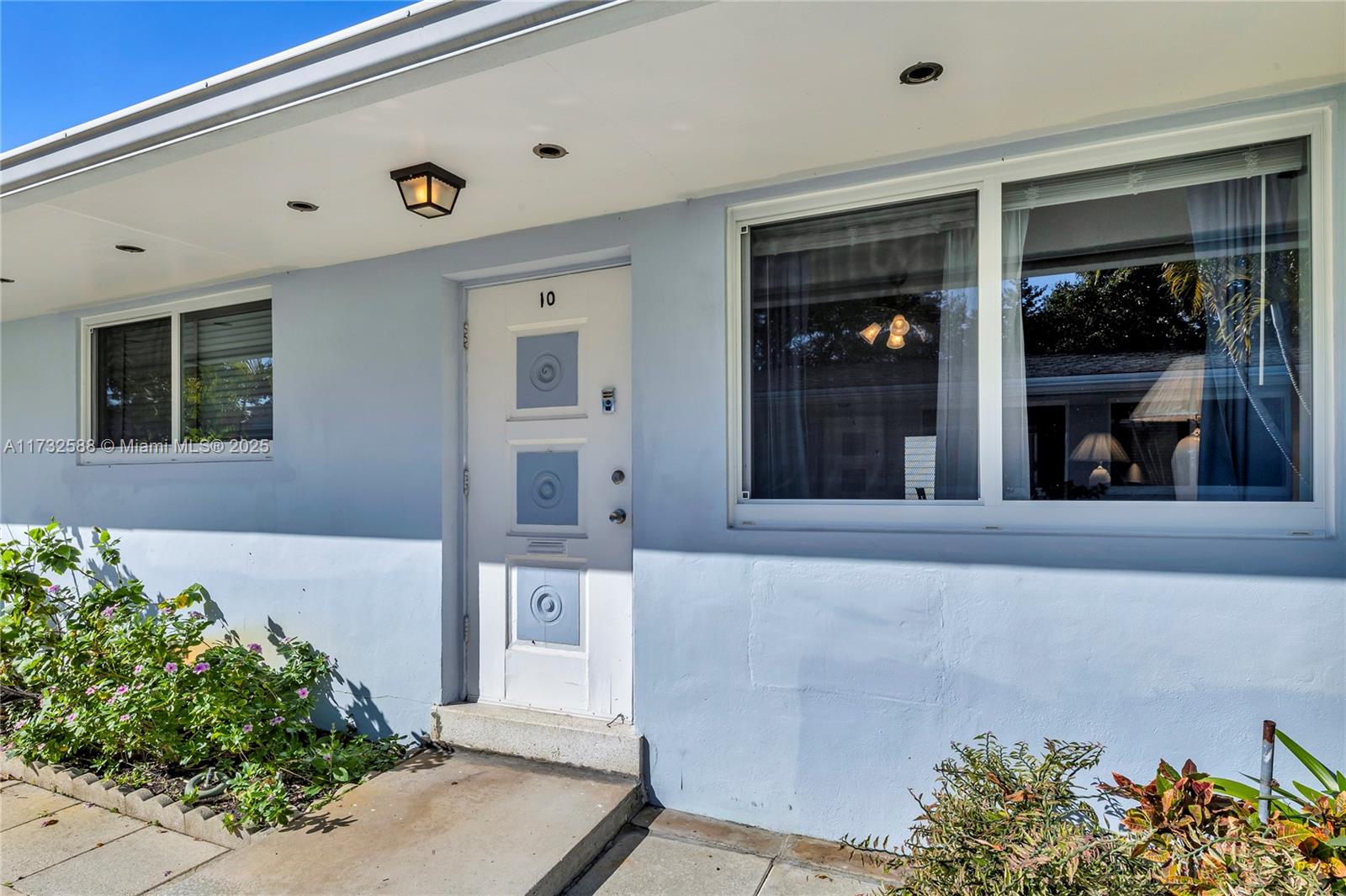 The exterior of a light blue house features a white front door and a window — 2300 Jackson St # 10, Hollywood FL 33020, HOLLYWOOD, FL