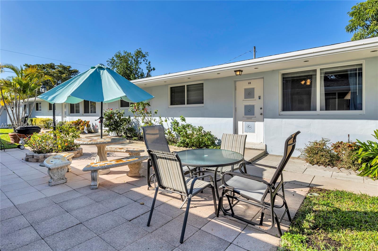A patio area with outdoor furniture, a blue umbrella, and a light-colored building exterior — 2300 Jackson St # 10, Hollywood FL 33020, HOLLYWOOD, FL