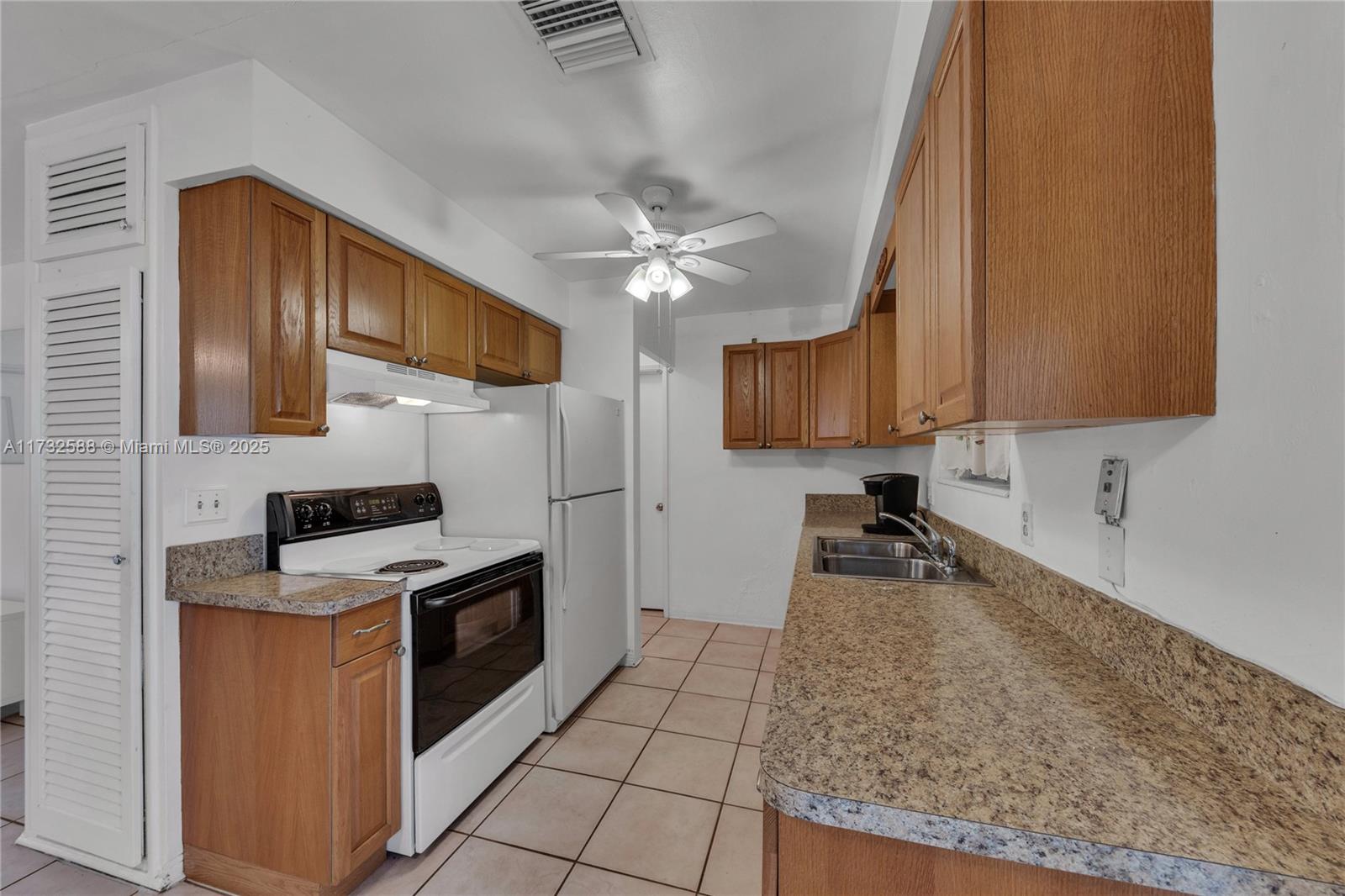 A kitchen features wooden cabinets, laminate countertops, white appliances, and tiled flooring — 2300 Jackson St # 10, Hollywood FL 33020, HOLLYWOOD, FL