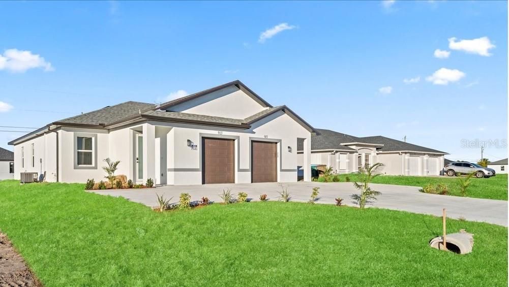 A modern duplex with white stucco walls and two brown garage doors under a blue sky — 1812/1814 NE 8TH PLACE, CAPE CORAL, FL