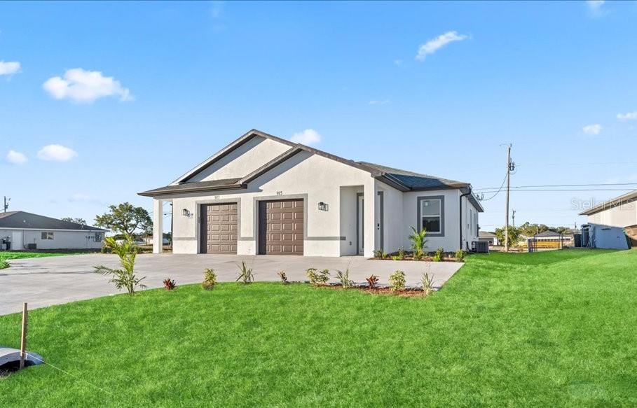 A single-story duplex with two garage doors and a light-colored stucco exterior — 1812/1814 NE 8TH PLACE, CAPE CORAL, FL