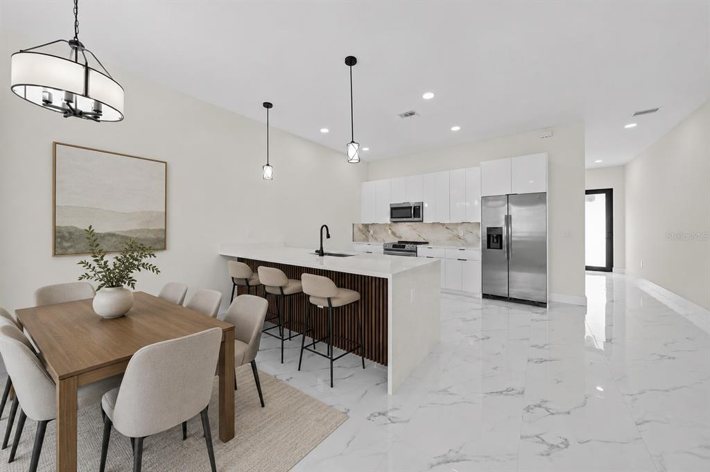 A modern kitchen and dining area features white cabinets, marble floors, and a wood-slatted island — 1812/1814 NE 8TH PLACE, CAPE CORAL, FL