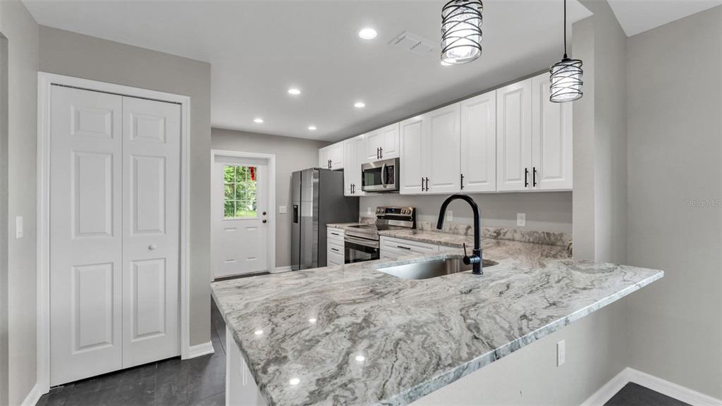 A kitchen features white cabinets, granite countertops, a stainless steel refrigerator, and a breakfast bar — 0 38TH STREET NW, WINTER HAVEN, FL
