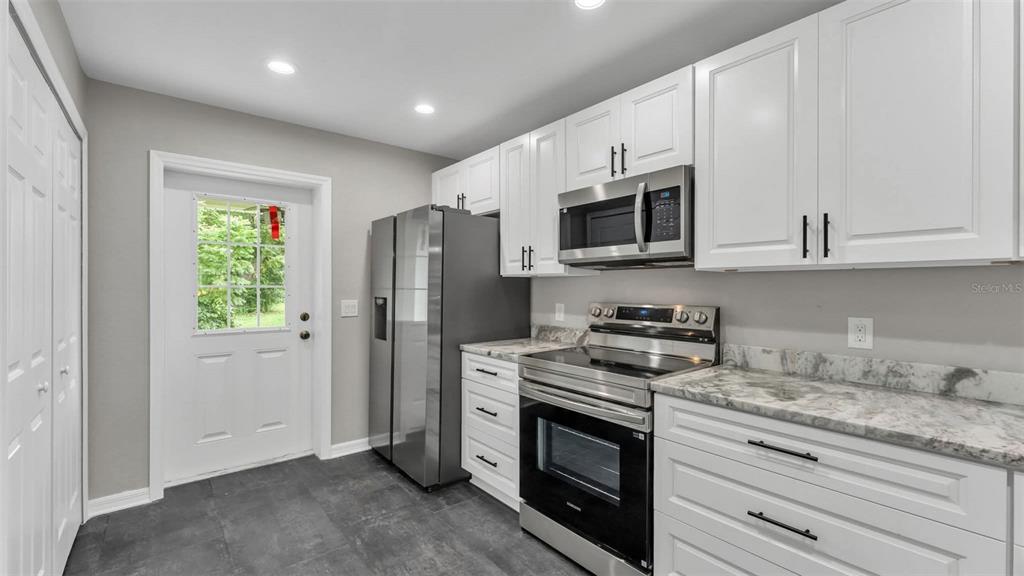 A kitchen featuring white cabinets, stainless steel appliances, and a marble-patterned countertop — 0 38TH STREET NW, WINTER HAVEN, FL