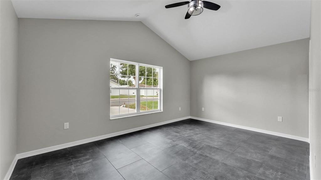 A room with gray walls, dark tile flooring, a vaulted ceiling, and a ceiling fan — 0 38TH STREET NW, WINTER HAVEN, FL