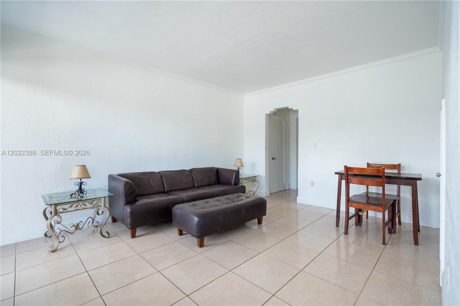 A living room features a brown leather sofa, a matching ottoman, and a dining set — 7435 Harding Ave # 204, Miami Beach FL 33141, MIAMI BEACH, FL