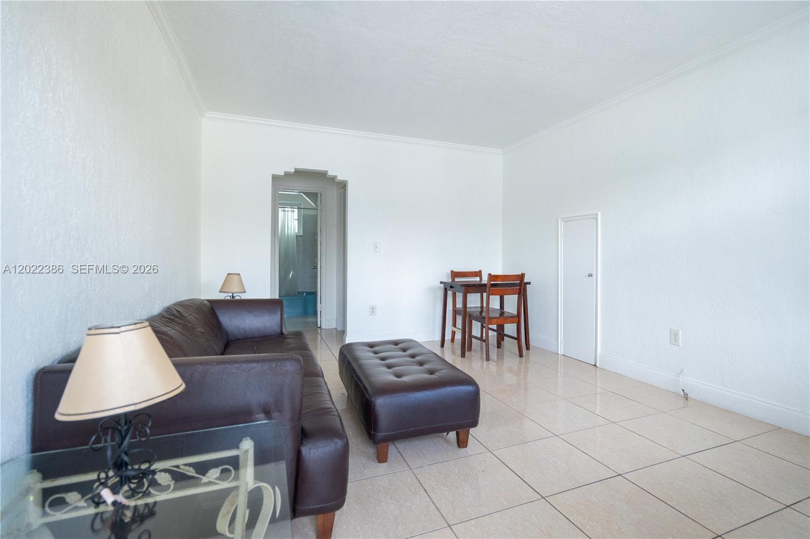 A brown leather sofa and ottoman sit between two glass-topped side tables on tile floors — 7435 Harding Ave # 204, Miami Beach FL 33141, MIAMI BEACH, FL
