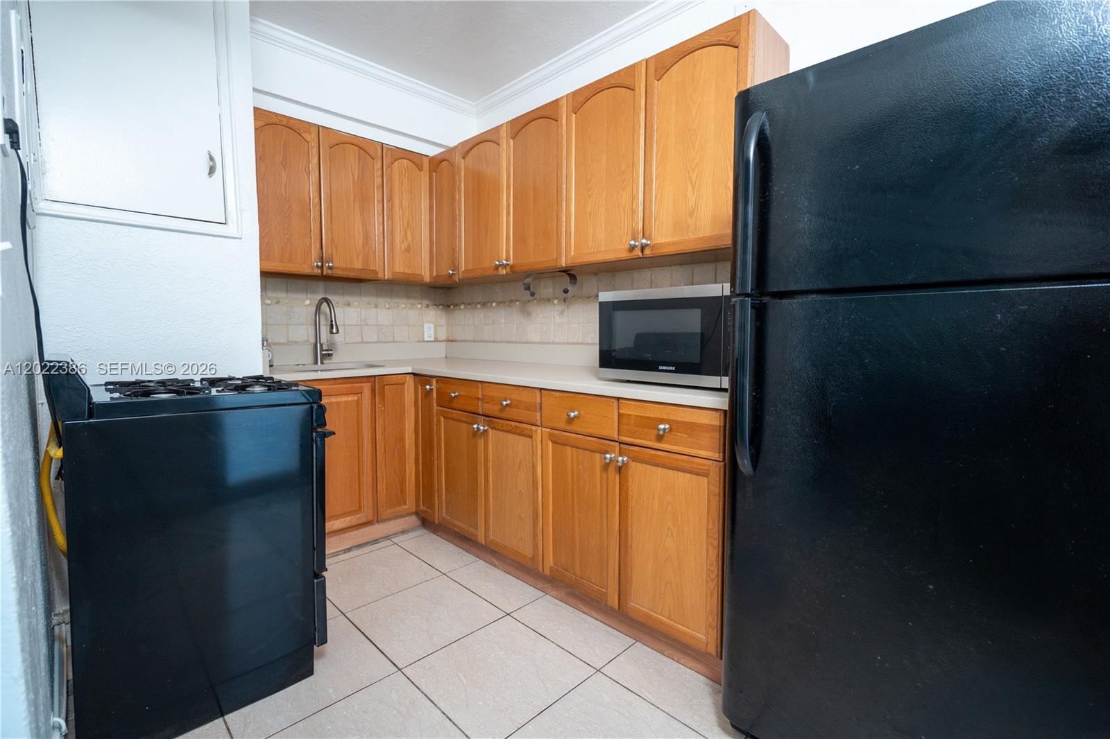 A living room features a brown leather sofa, an ottoman, and a small dining set — 7435 Harding Ave # 204, Miami Beach FL 33141, MIAMI BEACH, FL
