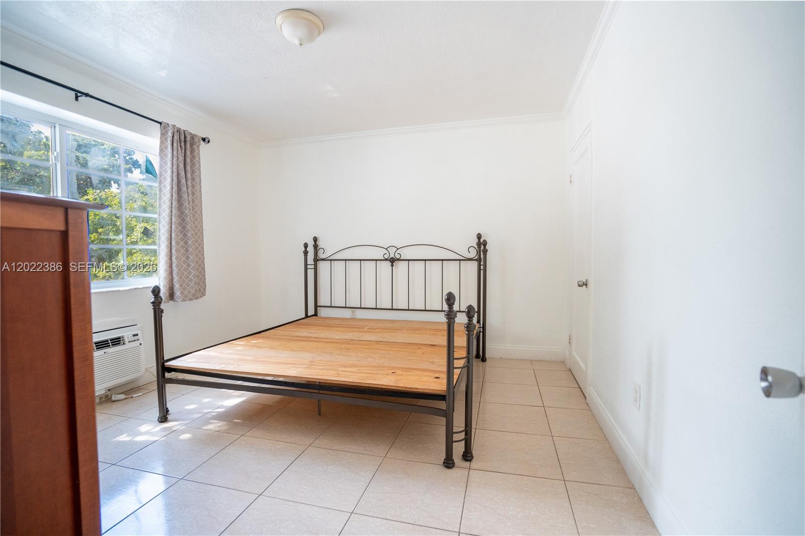 A kitchen features wood cabinets, black appliances, tile flooring, and a neutral backsplash — 7435 Harding Ave # 204, Miami Beach FL 33141, MIAMI BEACH, FL