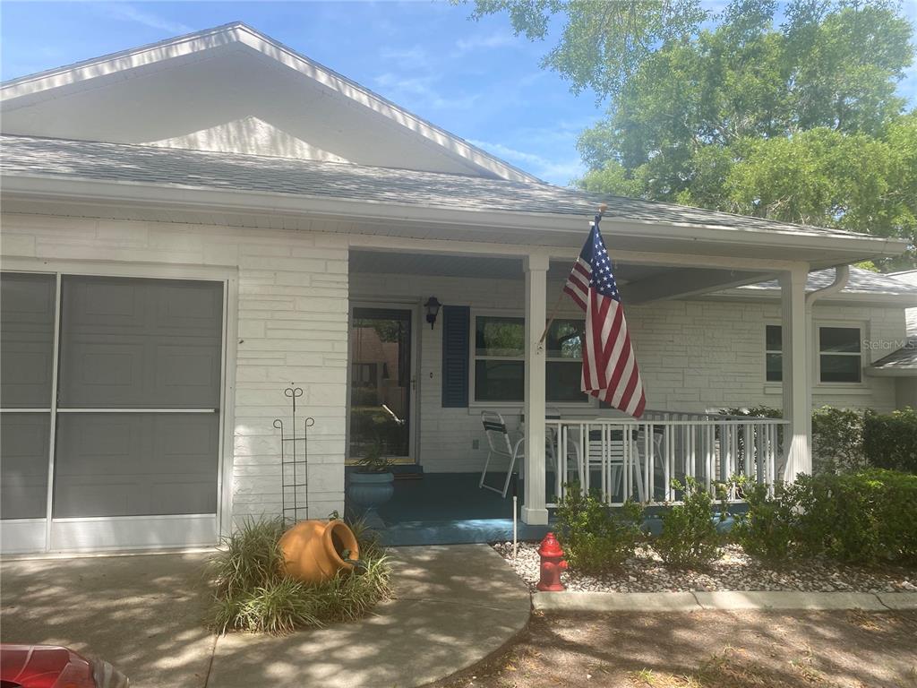 The exterior of a white brick house features a front porch with a flag — 9802 SW 88TH TERRACE UNIT C, OCALA, FL