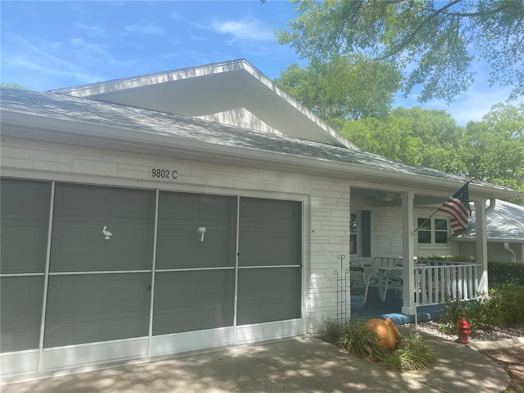 A white brick exterior features a garage with screen doors and a covered front porch — 9802 SW 88TH TERRACE UNIT C, OCALA, FL