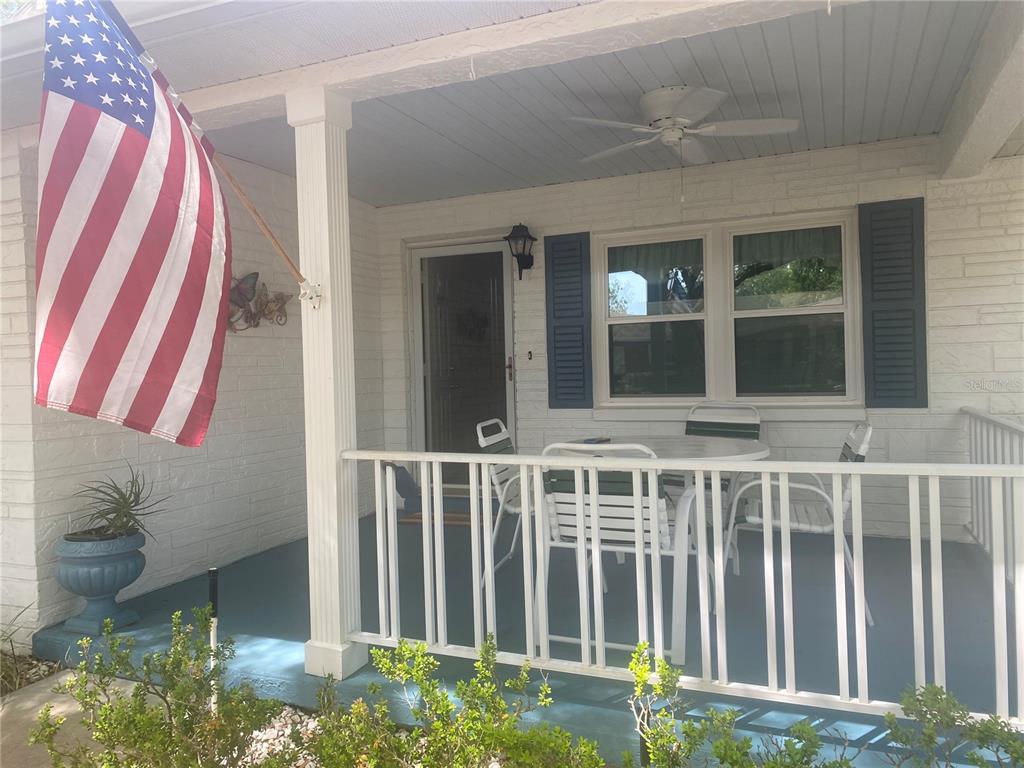 A covered front porch features a white railing, blue painted floor, and a dining set — 9802 SW 88TH TERRACE UNIT C, OCALA, FL