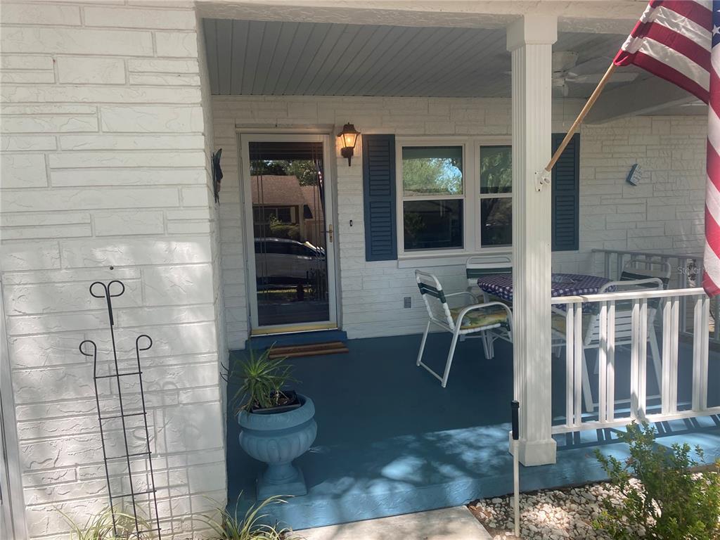A covered front porch features a blue painted floor, white brick walls, and outdoor furniture — 9802 SW 88TH TERRACE UNIT C, OCALA, FL