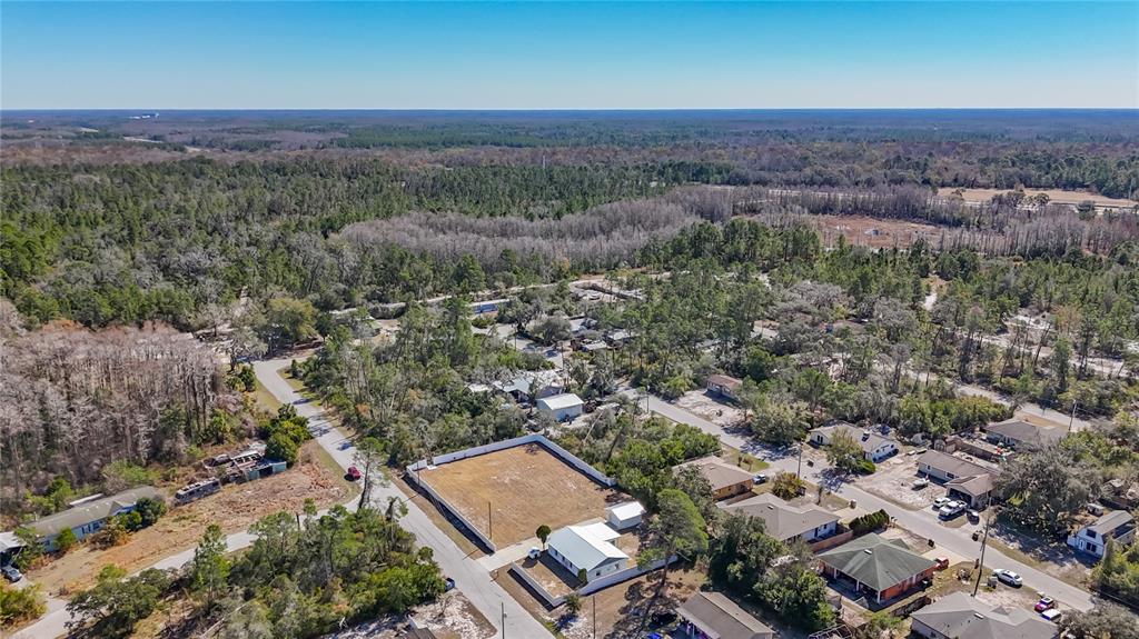 An aerial view shows a residential neighborhood with a cleared, fenced lot and surrounding homes — 12832 MOUNTAIN ROAD, NEW PORT RICHEY, FL