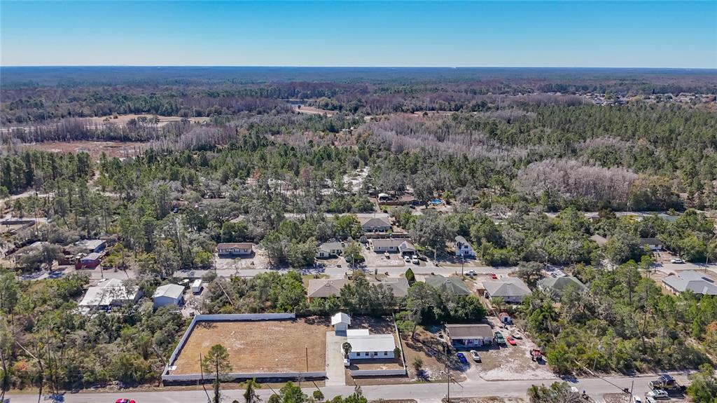 An aerial view shows a residential neighborhood with houses, a vacant lot, and surrounding woods — 12832 MOUNTAIN ROAD, NEW PORT RICHEY, FL