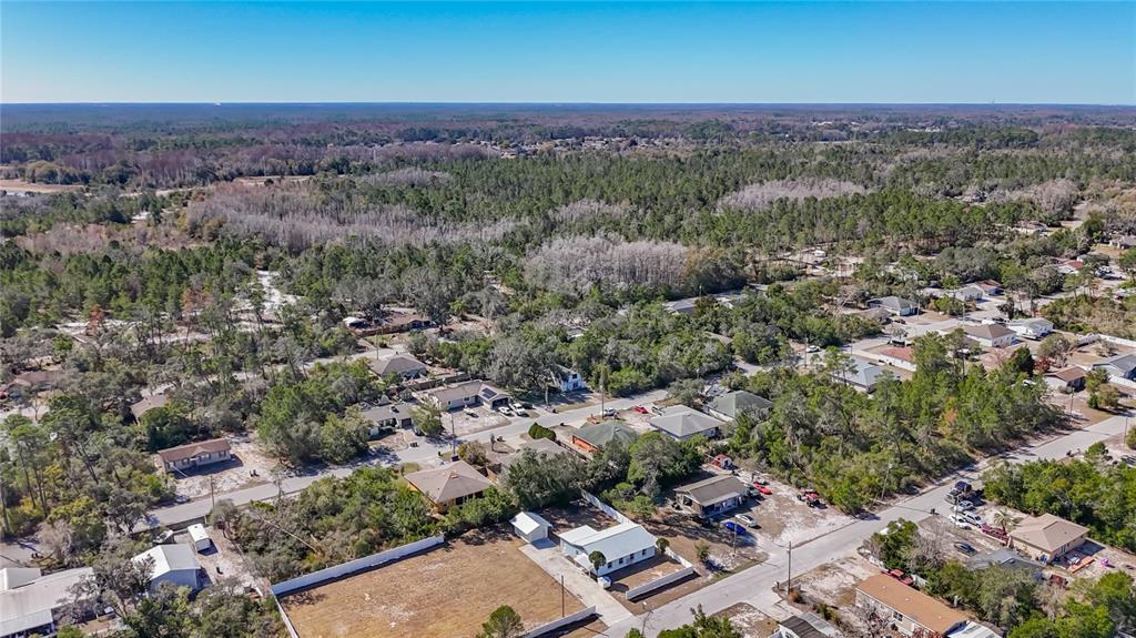 An aerial view shows a residential neighborhood with houses surrounded by trees and sandy lots — 12832 MOUNTAIN ROAD, NEW PORT RICHEY, FL