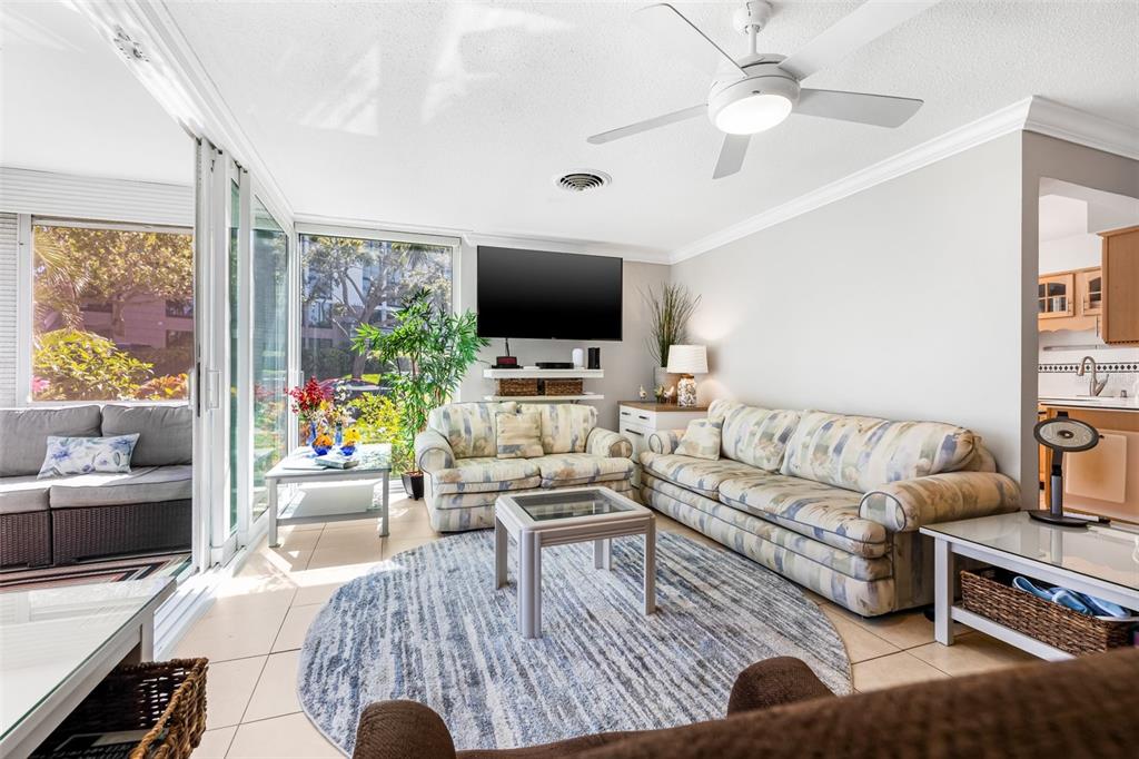 A living room features a patterned sofa, a round rug, and a ceiling fan — 615 10TH AVENUE NE UNIT 1, ST PETERSBURG, FL