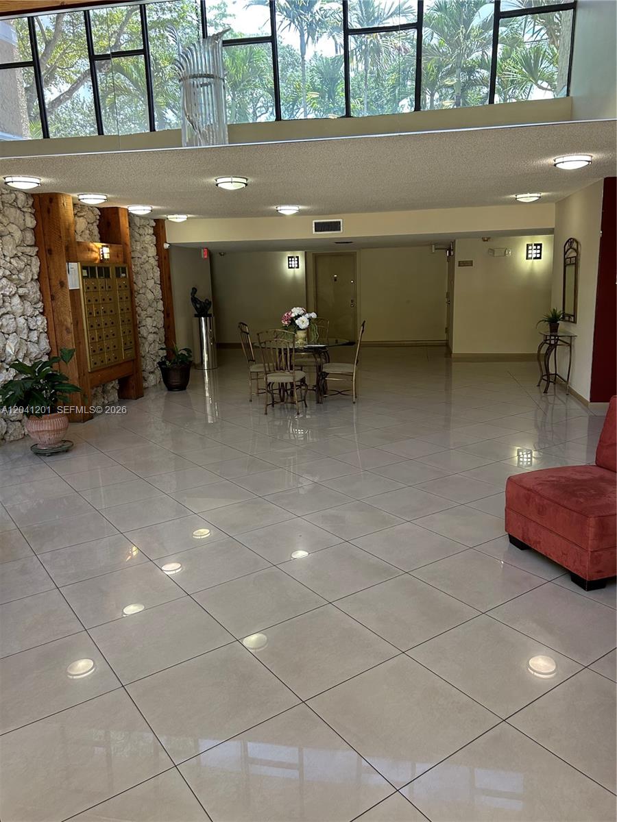 A spacious lobby features tile flooring, a stone accent wall, mailboxes, and a seating area — 16325 Golf Club Rd # 304, Weston FL 33326, WESTON, FL
