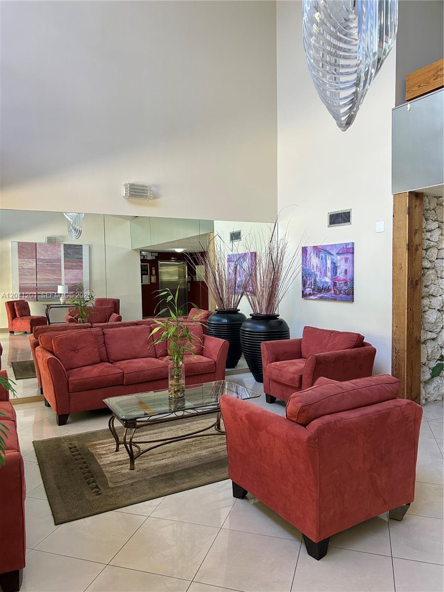 A lobby area features red upholstered furniture, a glass coffee table, and large wall mirrors — 16325 Golf Club Rd # 304, Weston FL 33326, WESTON, FL