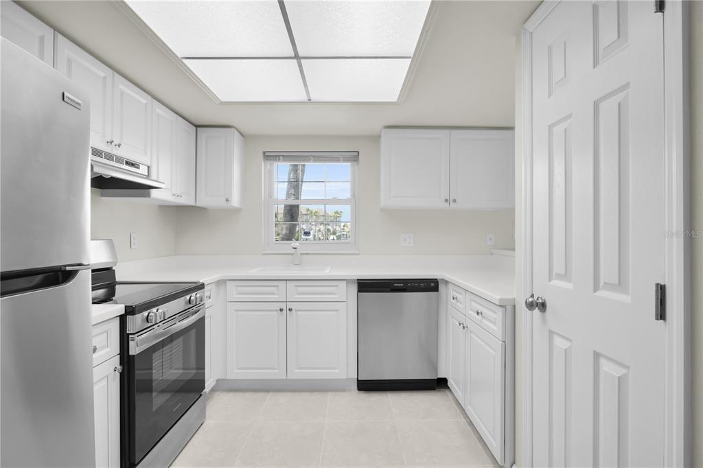 A kitchen features white cabinets, stainless steel appliances, and a window above the sink — 8820 BAY POINTE DRIVE UNIT 102, TAMPA, FL