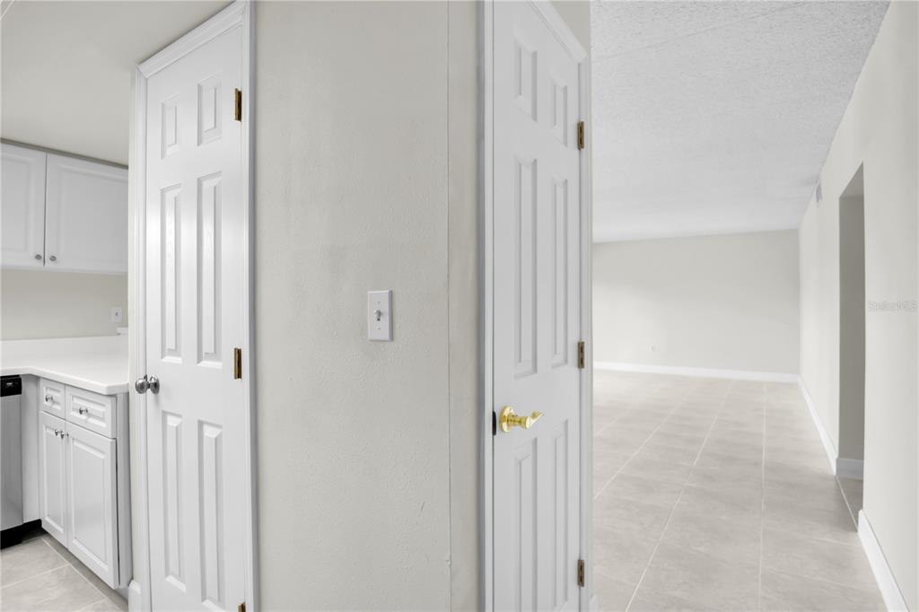 A white door stands between a kitchen area and a tiled hallway leading to a room — 8820 BAY POINTE DRIVE UNIT 102, TAMPA, FL