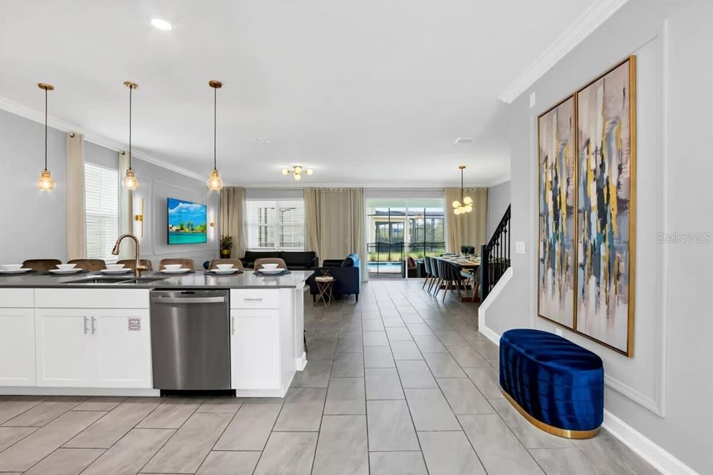 An open-concept kitchen and living area features white cabinetry, tile flooring, and a dining space — 4388 QUOTE STREET, KISSIMMEE, FL