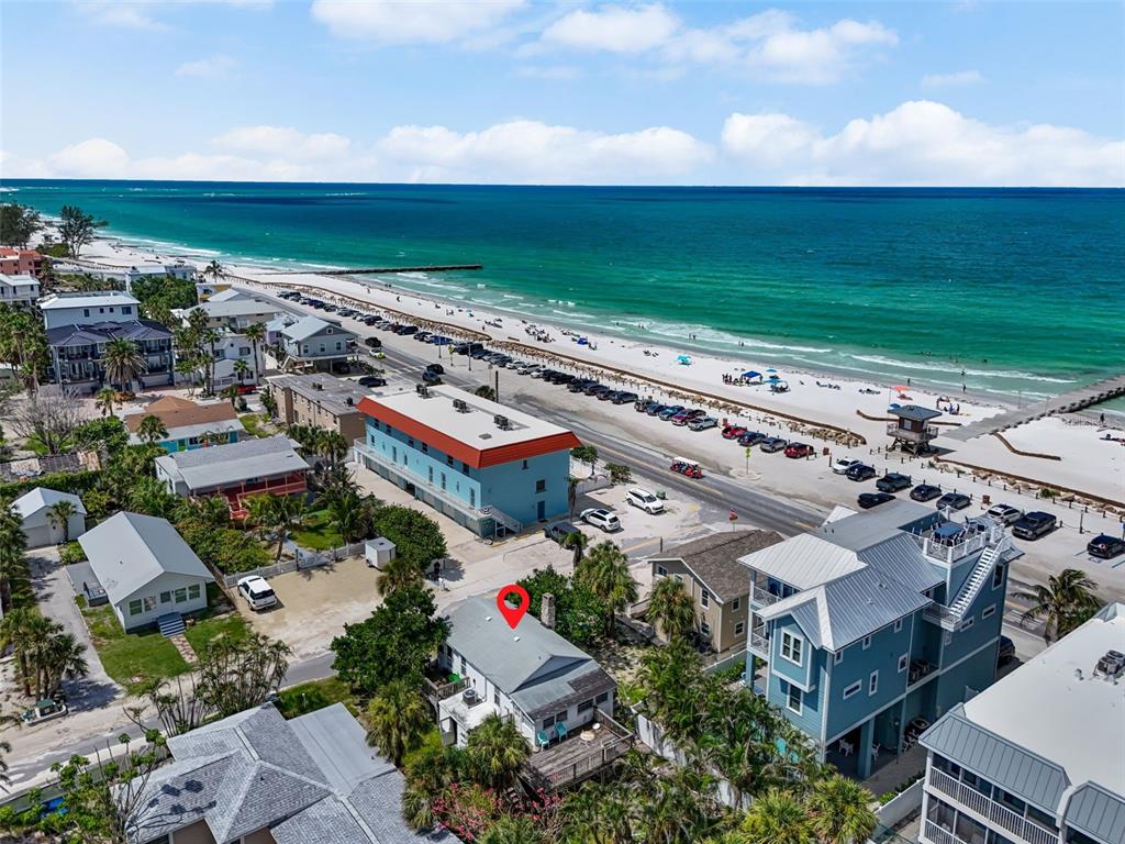 An aerial view shows a beachside neighborhood with a red-marked house near the ocean — 104 10TH STREET S, BRADENTON BEACH, FL