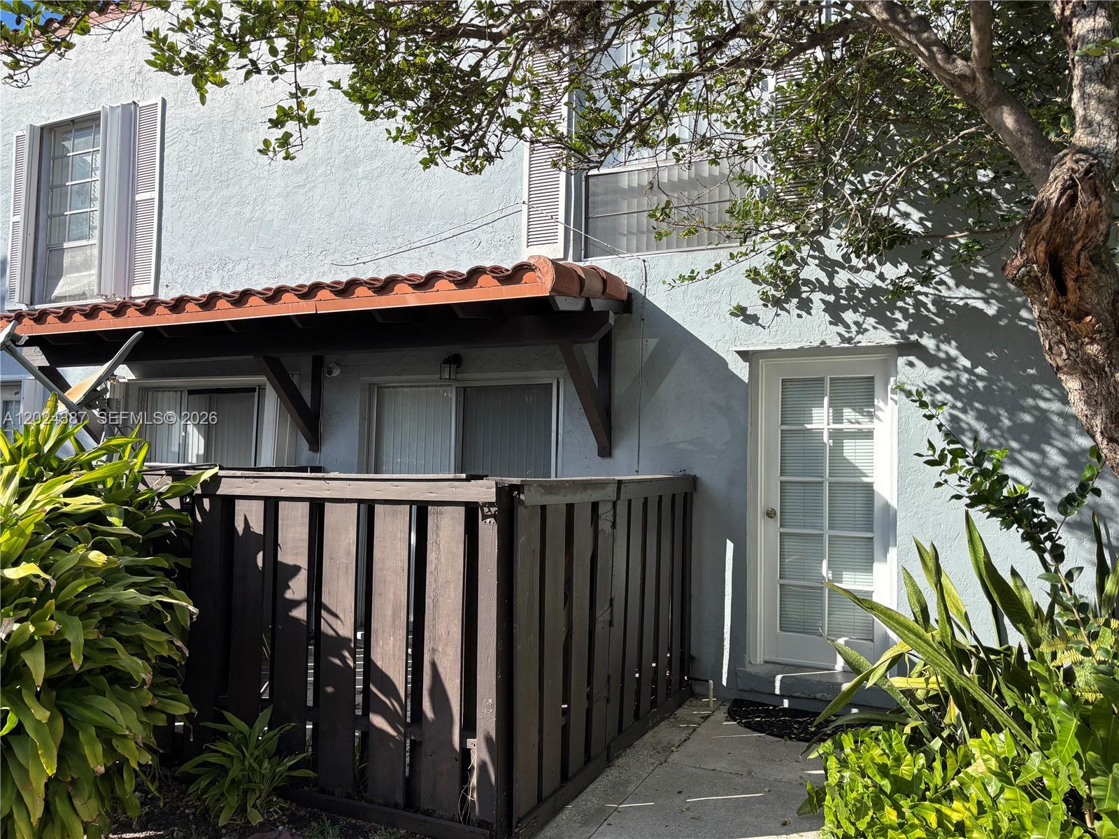 A patio with a wooden fence and a tiled awning sits beside a white door — 10806 N Kendall Dr # 26, Miami FL 33176, MIAMI, FL