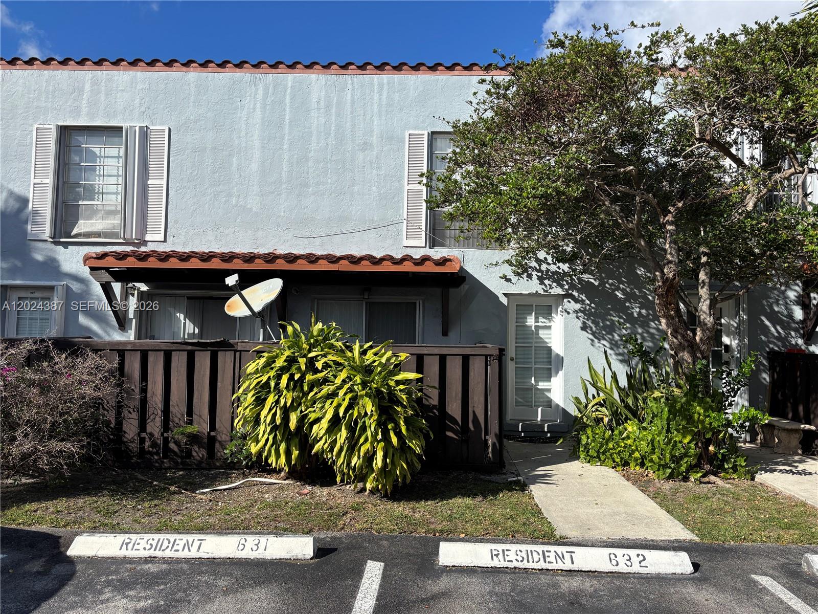 A two-story residential building with a brown wooden fence, parking spaces, and a large tree — 10806 N Kendall Dr # 26, Miami FL 33176, MIAMI, FL