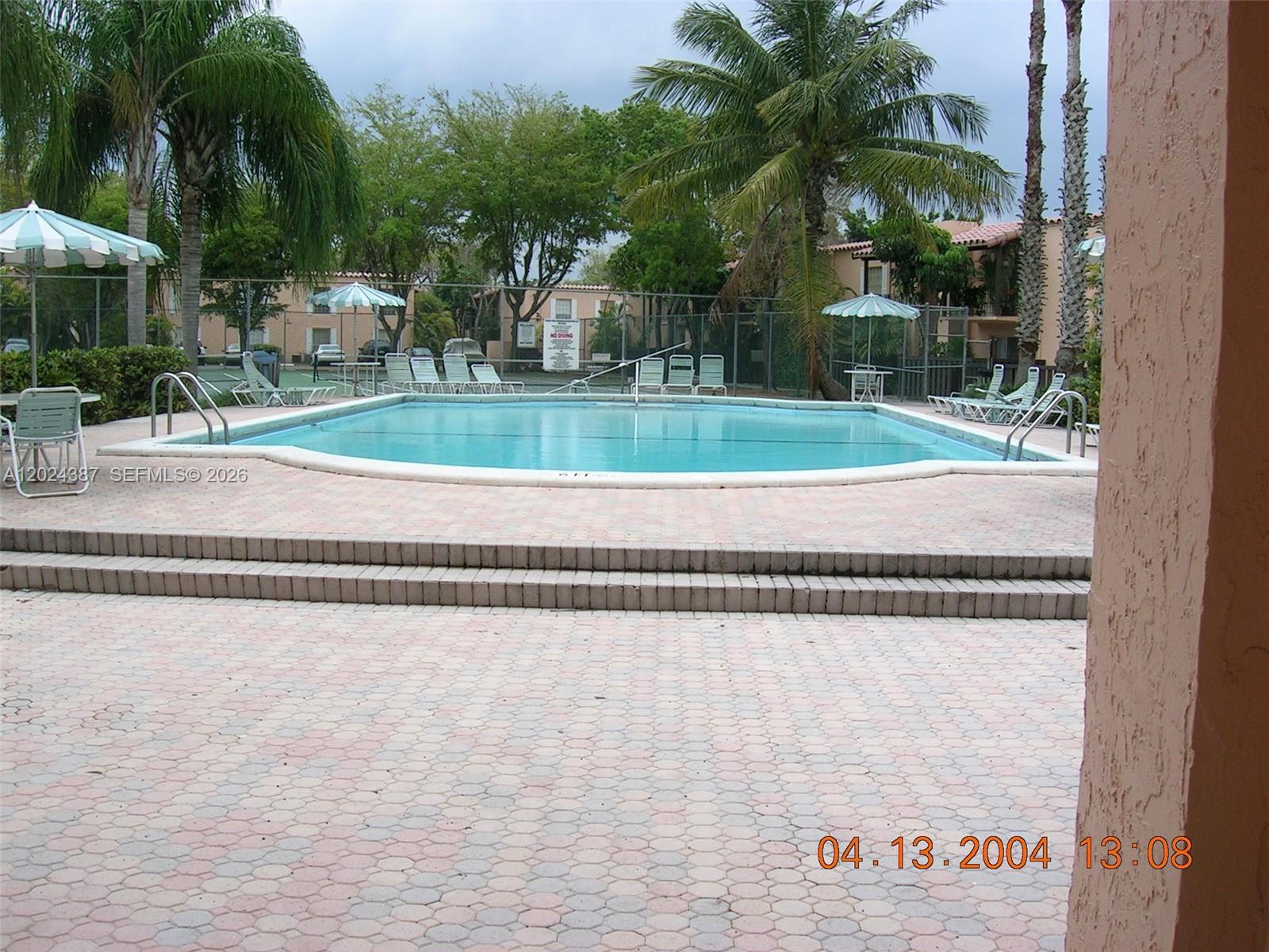 A rectangular swimming pool is surrounded by a paved deck, lounge chairs, and palm trees — 10806 N Kendall Dr # 26, Miami FL 33176, MIAMI, FL