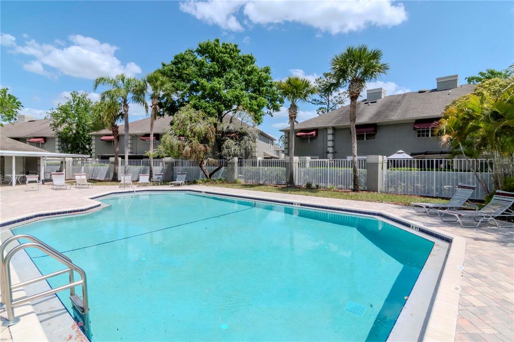 A swimming pool with lounge chairs sits in front of a multi-story apartment building — 14053 NOTREVILLE WAY, TAMPA, FL