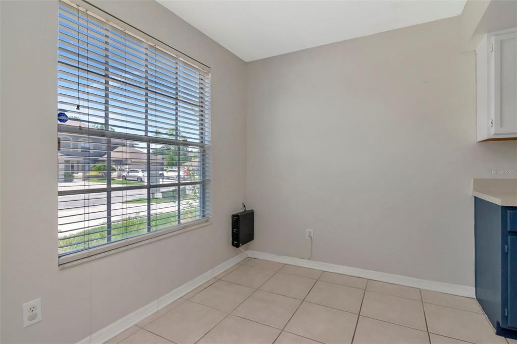 A small dining area features light tile flooring, a large window with blinds, and beige walls — 14053 NOTREVILLE WAY, TAMPA, FL