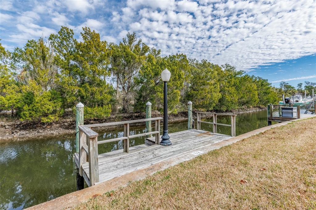 A wooden boat dock with a lamp post sits along a narrow canal by trees — 11346 W BAYSHORE DRIVE UNIT 52, CRYSTAL RIVER, FL