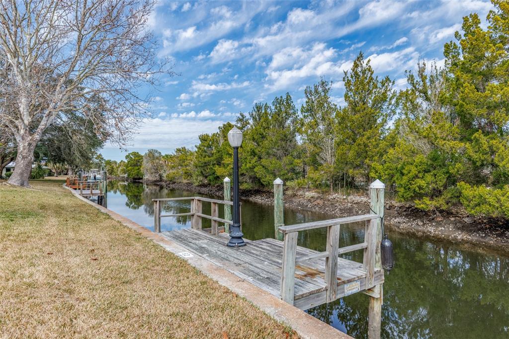A wooden dock with a lamp post sits along a narrow canal lined with trees — 11346 W BAYSHORE DRIVE UNIT 52, CRYSTAL RIVER, FL