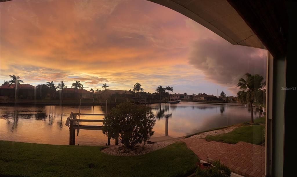A view of a canal at sunset from a patio with a boat dock — 3433 NIGHTHAWK COURT, PUNTA GORDA, FL