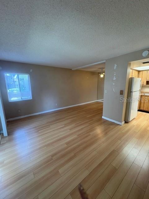 An open-concept living area features light wood-look flooring and a view into the kitchen — 1839 BOUGH AVENUE UNIT B, CLEARWATER, FL
