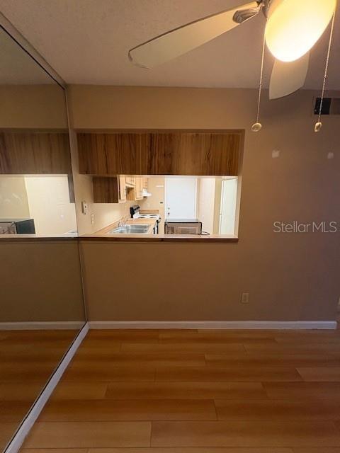 An empty room features light wood-look flooring, a ceiling fan, and a sliding glass door — 1839 BOUGH AVENUE UNIT B, CLEARWATER, FL