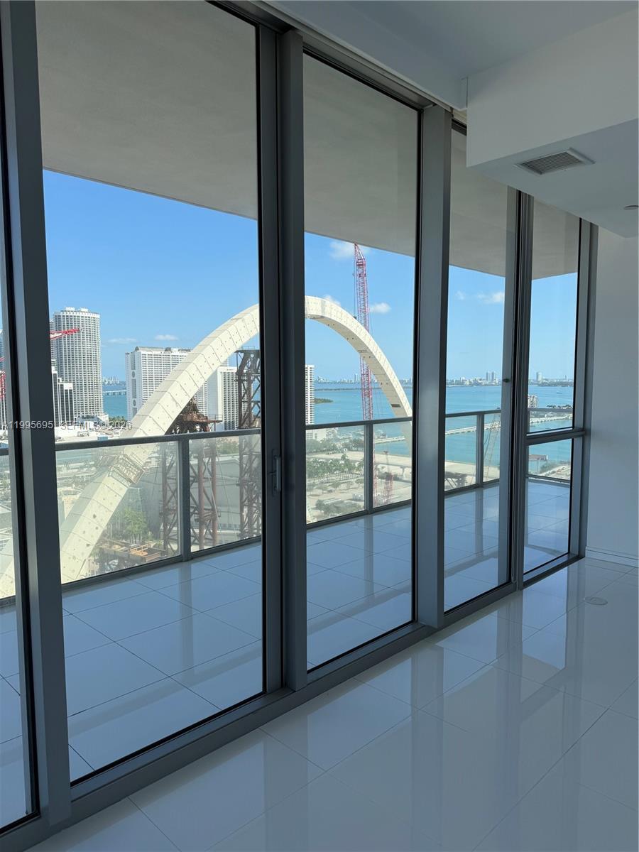 An interior view of a room with floor-to-ceiling windows overlooking a bridge construction site — 1100 Biscayne Blvd # 2605, Miami FL 33132, MIAMI, FL