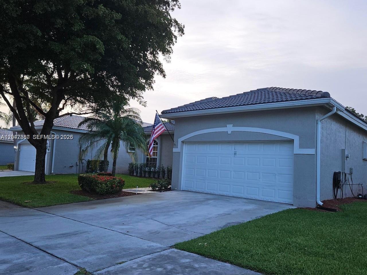 A single-story house with a two-car garage, a concrete driveway, and a large tree — 2635 SE 4th Pl, Homestead FL 33033, HOMESTEAD, FL