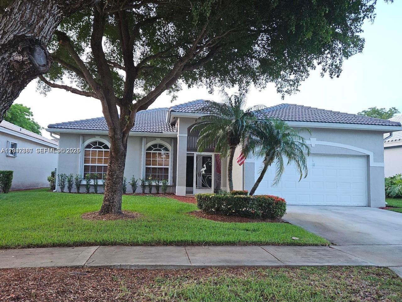 A single-story house with a tiled roof, arched windows, and a large tree in front — 2635 SE 4th Pl, Homestead FL 33033, HOMESTEAD, FL