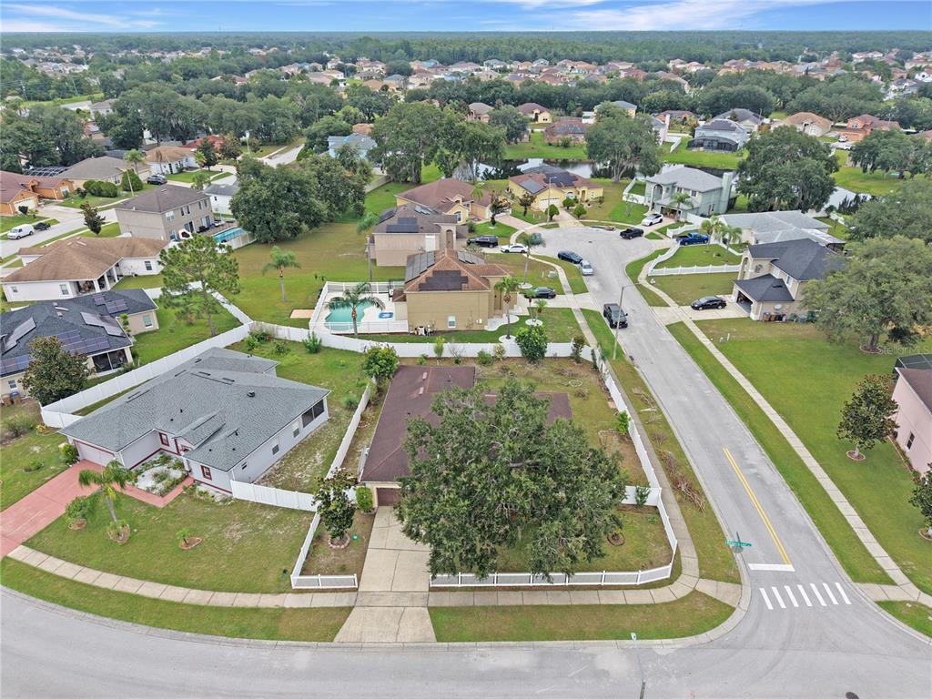 An aerial view shows a suburban neighborhood with single-family homes, fenced yards, and paved streets — 413 MARLBERRY LEAF AVENUE, KISSIMMEE, FL