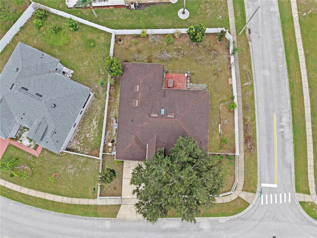 An aerial view shows a house with a brown roof, a large tree, and a fenced yard — 413 MARLBERRY LEAF AVENUE, KISSIMMEE, FL