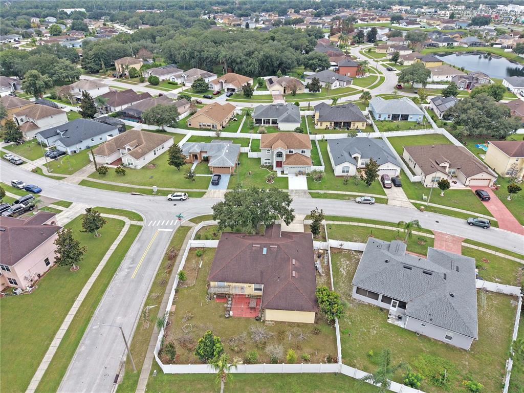 An aerial view shows a suburban neighborhood with single-family homes, paved streets, and green lawns — 413 MARLBERRY LEAF AVENUE, KISSIMMEE, FL