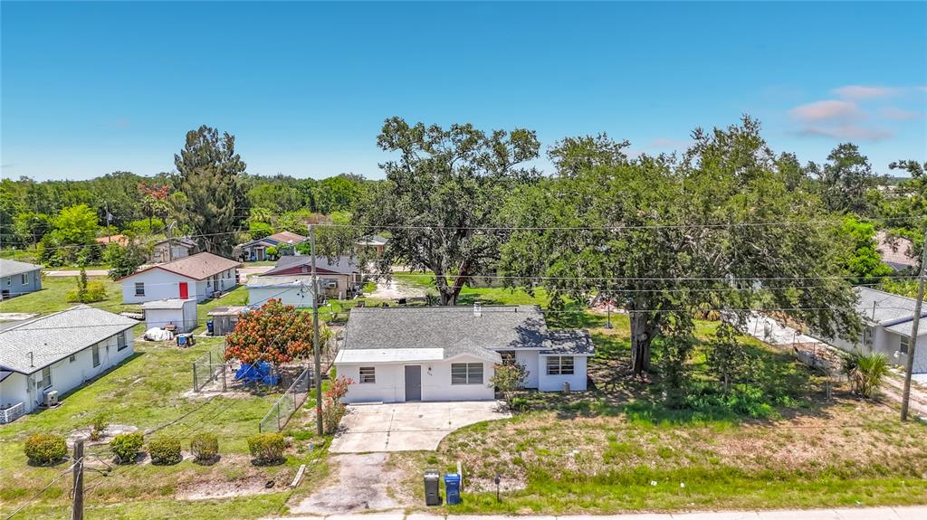 An aerial view shows a single-story white house with a gray roof and large trees — 220 29TH STREET E, PALMETTO, FL