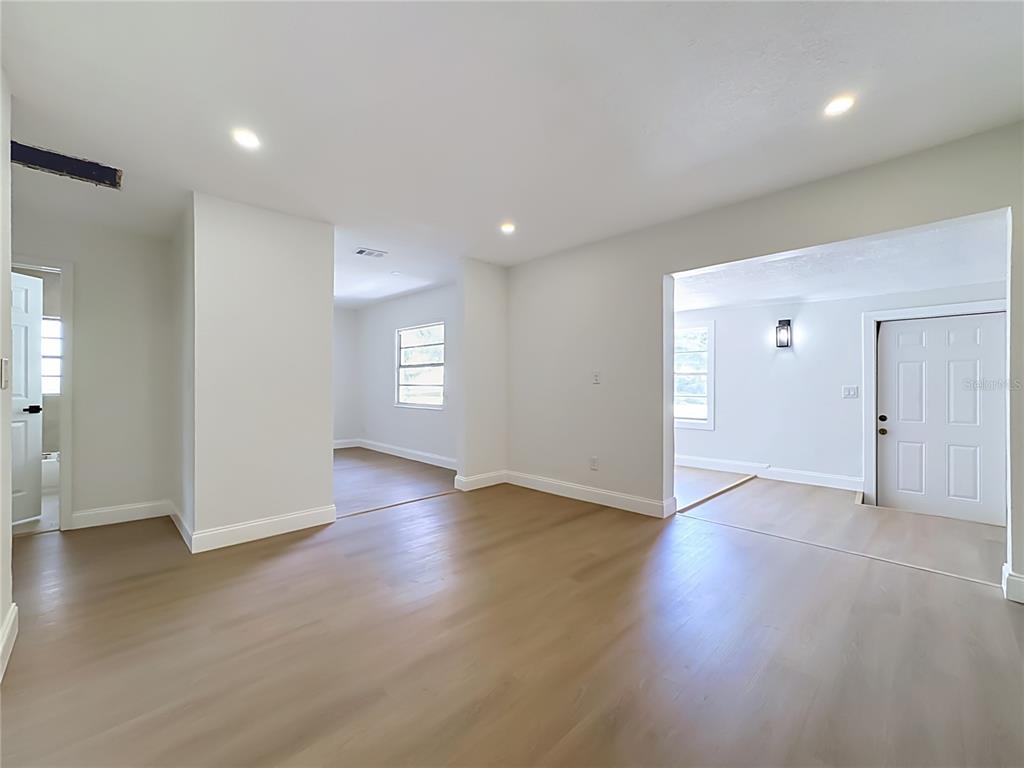 An interior view shows a living area with light wood flooring and white walls — 220 29TH STREET E, PALMETTO, FL