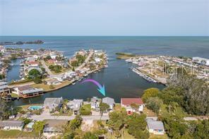 An aerial view shows a waterfront house with a purple arrow pointing toward it — 14217 HENDRY COURT, HUDSON, FL