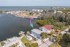 An aerial view shows a waterfront house with an RV parked beside it near a marina — 14217 HENDRY COURT, HUDSON, FL