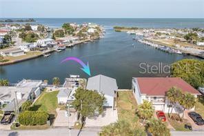 An aerial view shows a waterfront house with a gray roof next to a canal — 14217 HENDRY COURT, HUDSON, FL