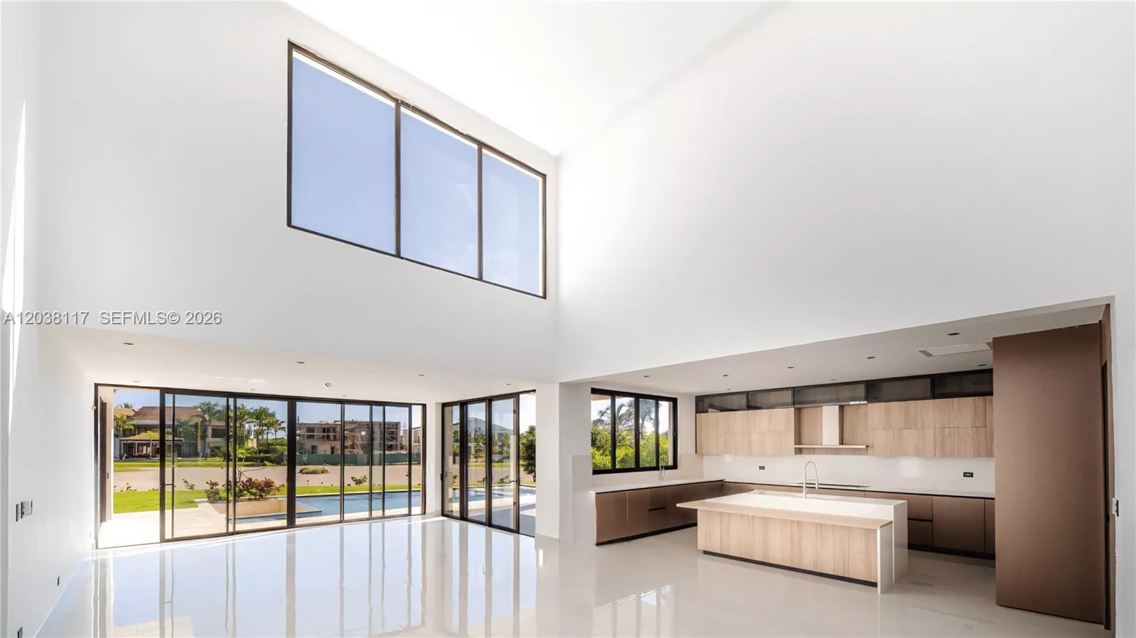 A modern, high-ceilinged open-concept kitchen and living area features white walls and tile floors — 0 sv las palmas, FL