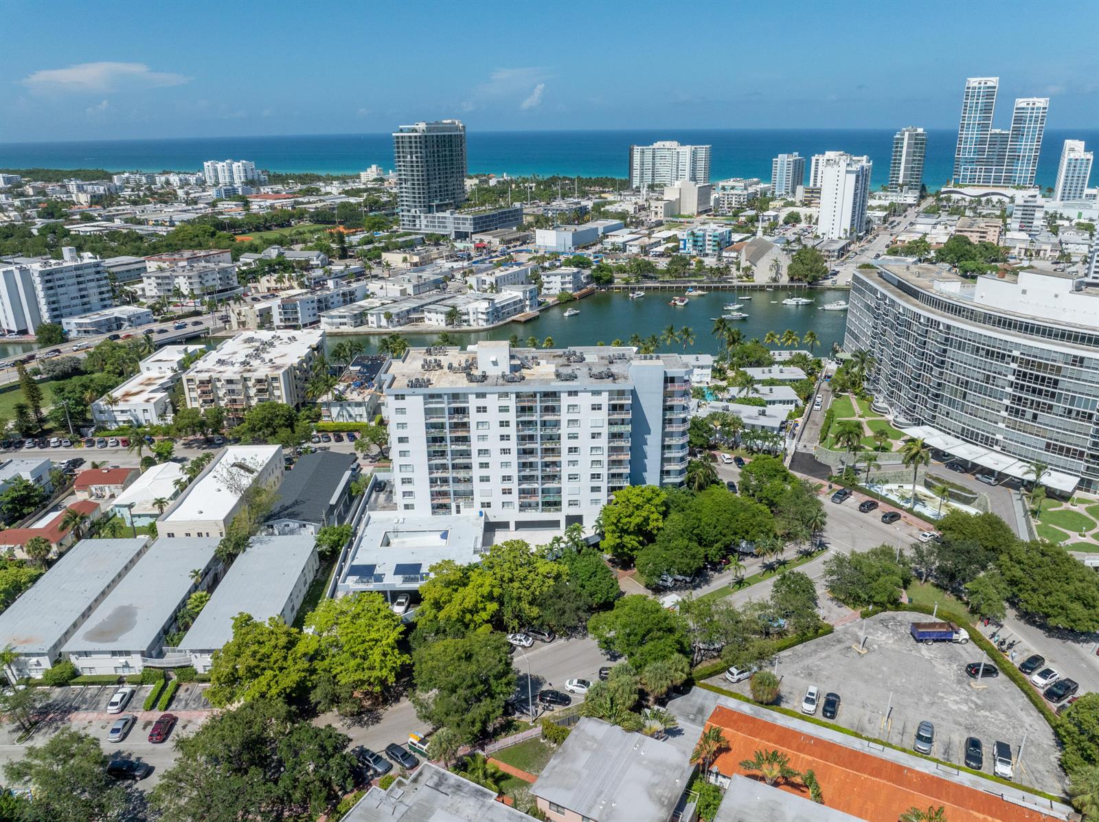 An aerial view shows a multi-story residential building surrounded by trees, parking lots, and water — 6900 Bay Drive # 11i, Miami Beach FL 33141, MIAMI BEACH, FL